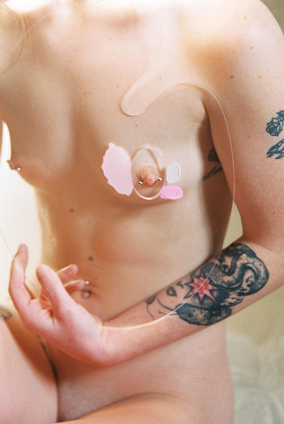 A woman's torso is visible, with a clear plastic sheet covering her chest and a hand resting on her stomach.