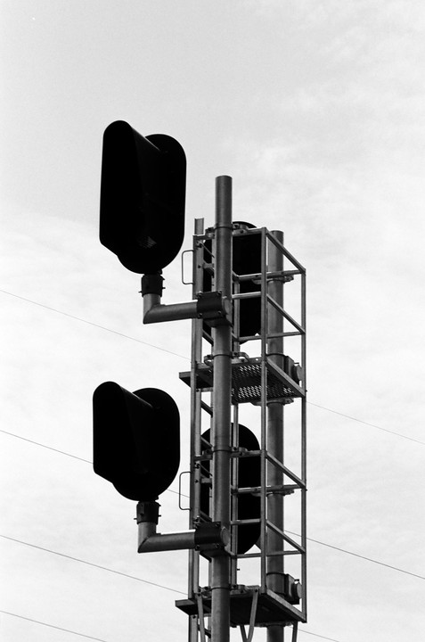A tall metal structure with multiple dark signal lights is set against a bright, overcast sky.