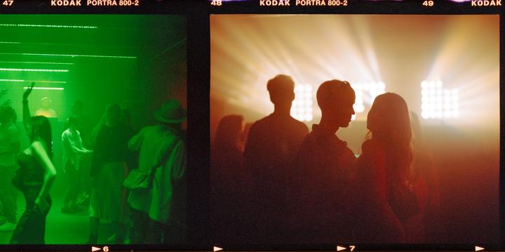 People are dancing in a nightclub with green and orange lighting.