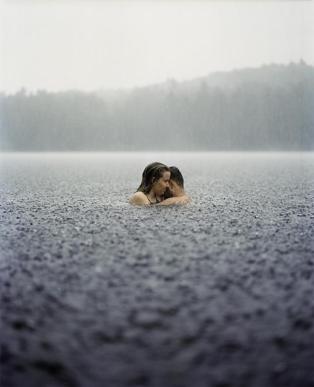 A couple embraces in a lake during a torrential downpour.