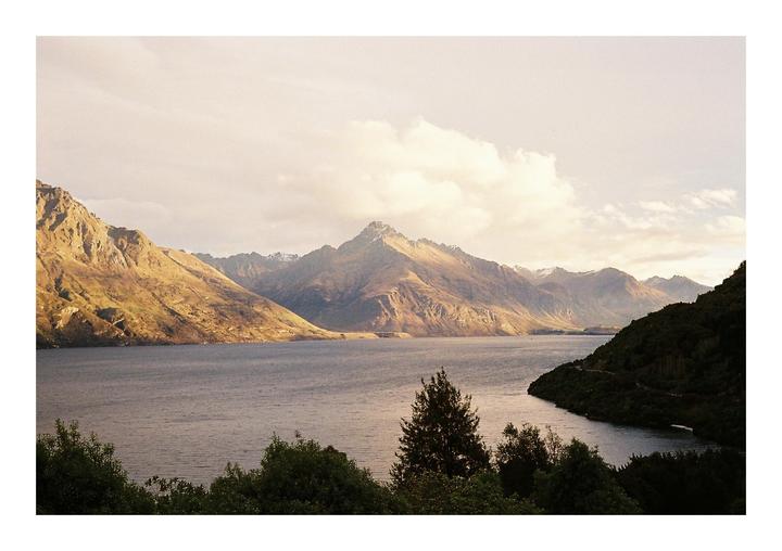A body of water is surrounded by mountains under a cloudy sky.