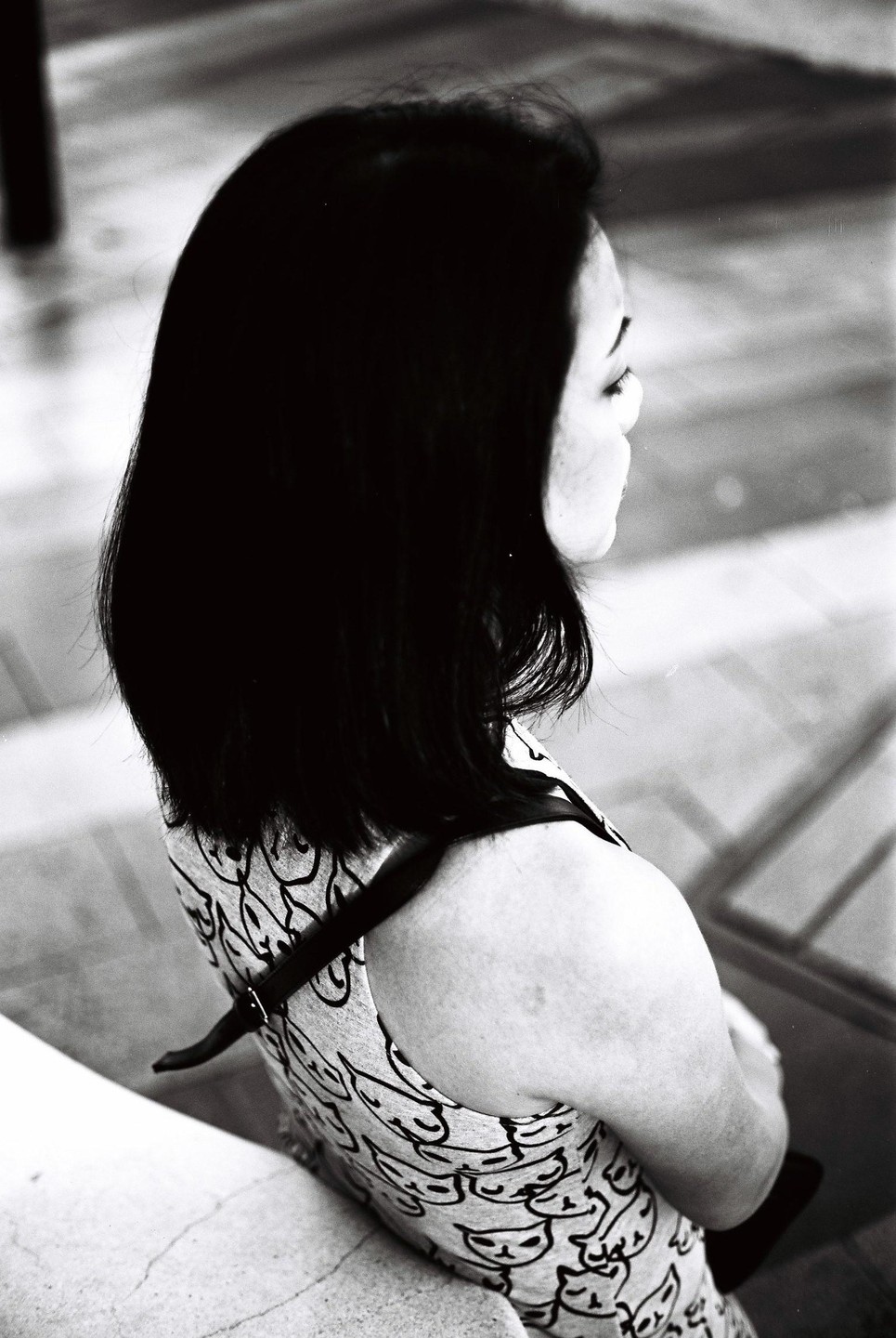 A woman with dark hair and a patterned top is seen from behind, looking to the right.