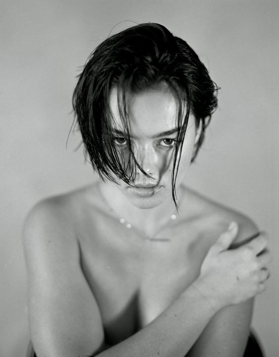 A woman with wet hair covering her face looks directly at the viewer.
