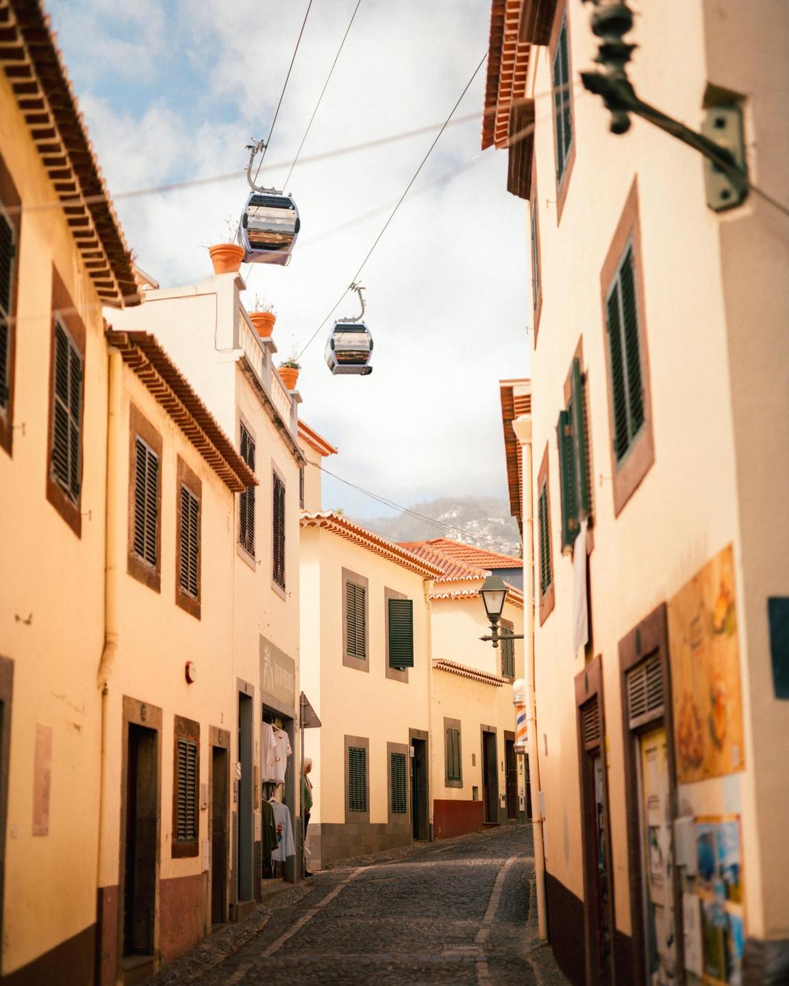 Two cable cars are visible above a narrow street lined with buildings.