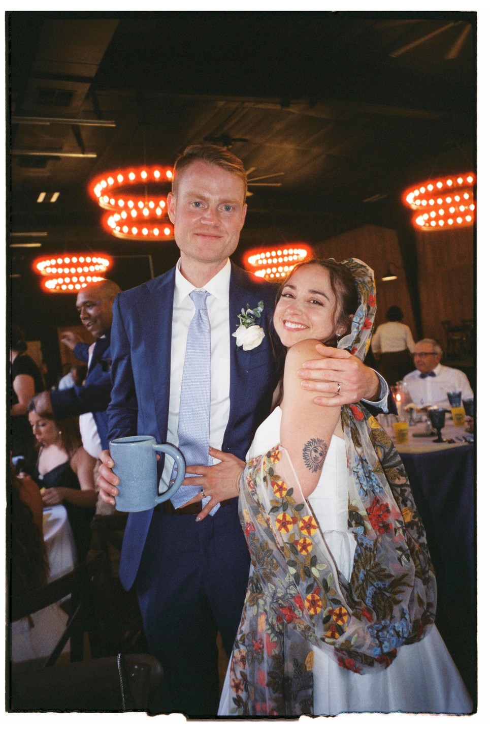 A couple poses for a photo at a wedding reception.