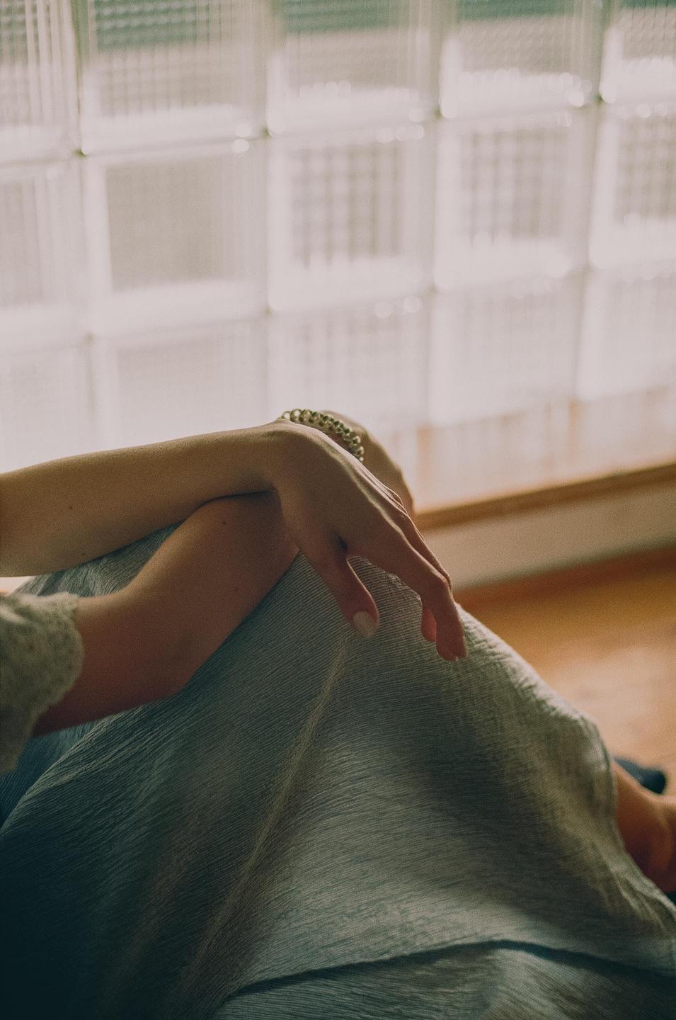A woman's arm and leg are visible in front of a glass block window.