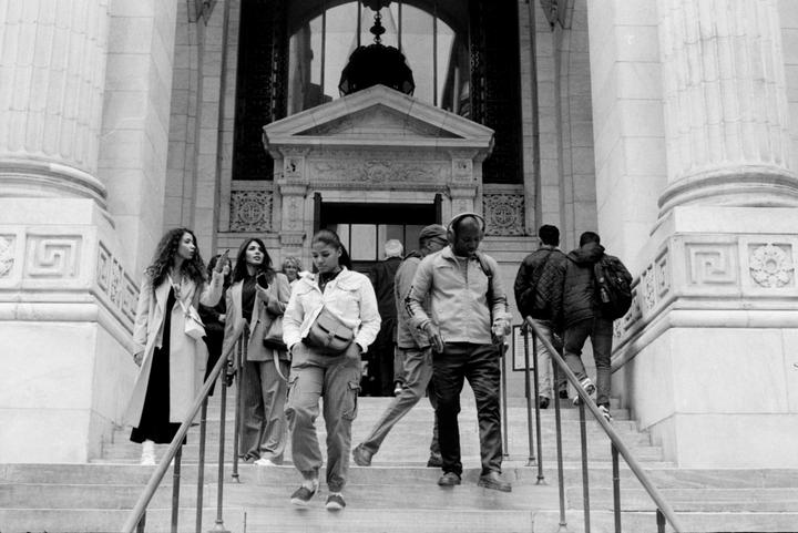 People walk up and down the steps of the New York Public Library.