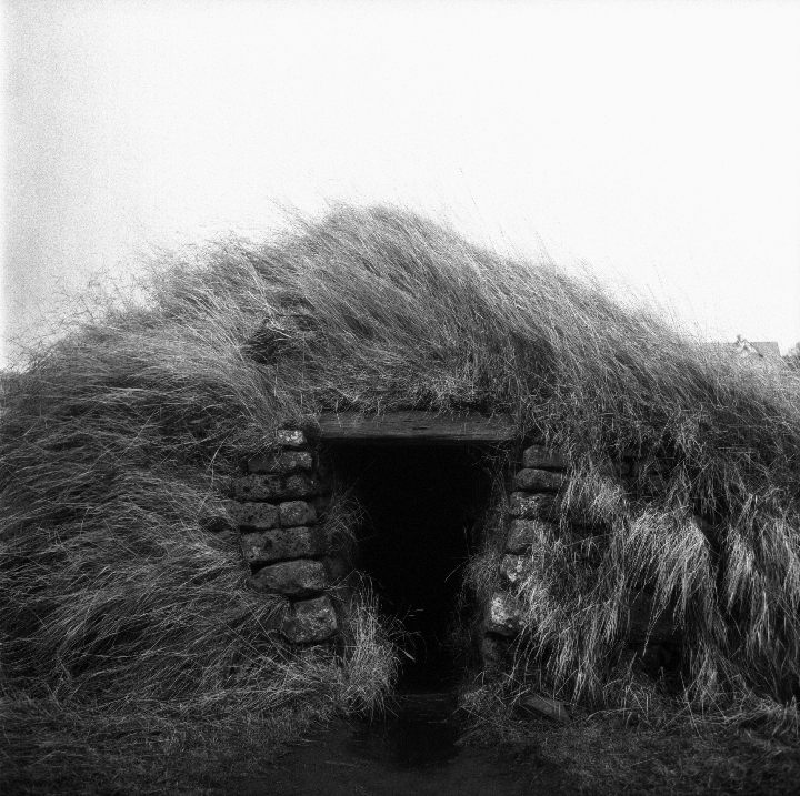 A small stone structure with a grass roof and entrance is shown.