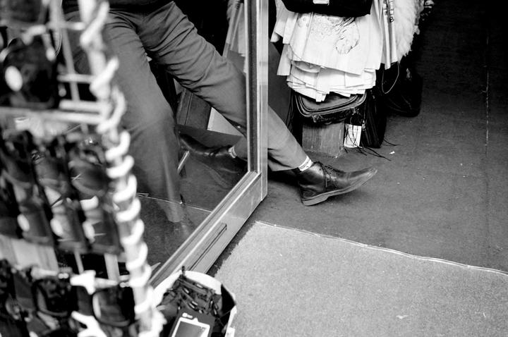 A person's legs and feet are visible, with one foot resting on the ground and the other reflected in a mirror.