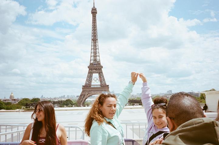 A group of people are gathered on a rooftop with the Eiffel Tower in the background.