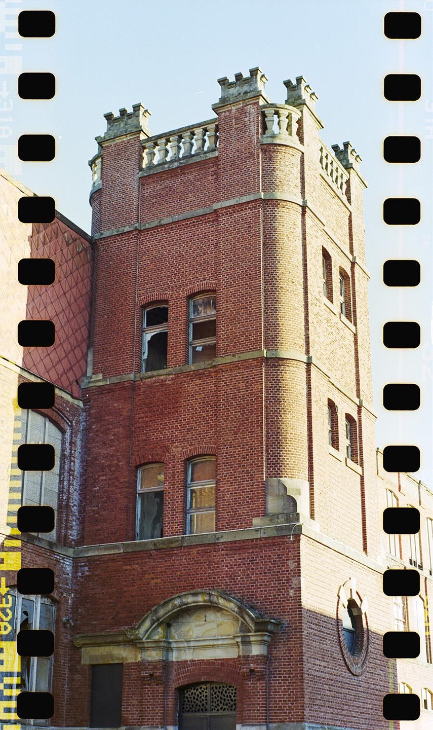 A tall brick tower with broken windows stands against a clear sky.