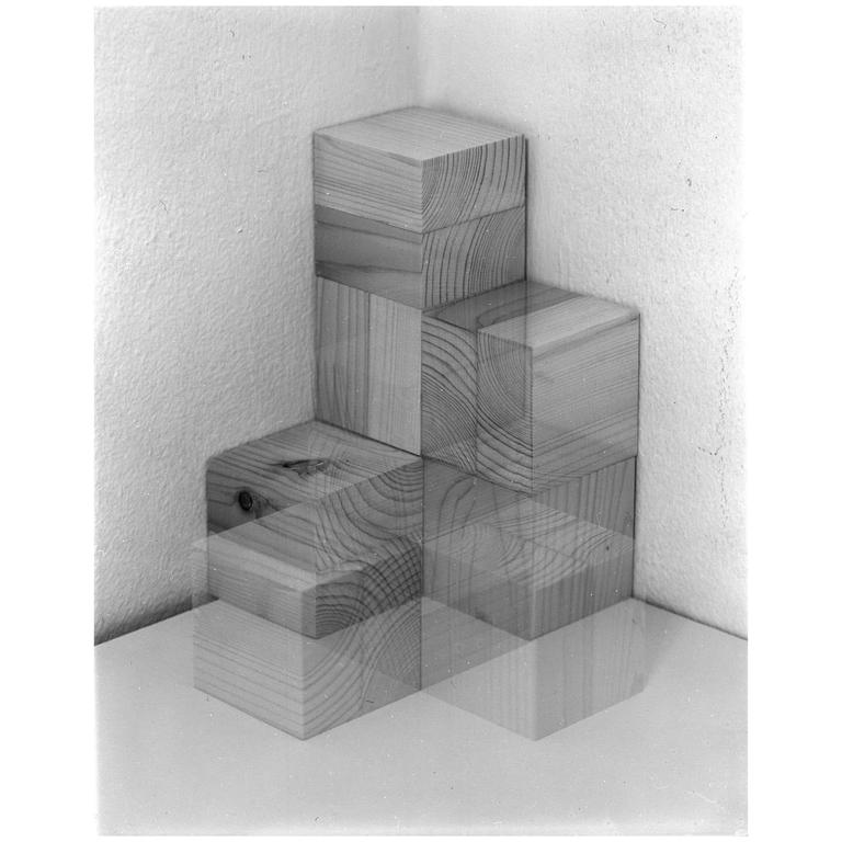 A stack of wooden blocks is arranged in a corner, with some blocks appearing translucent due to multiple exposures.