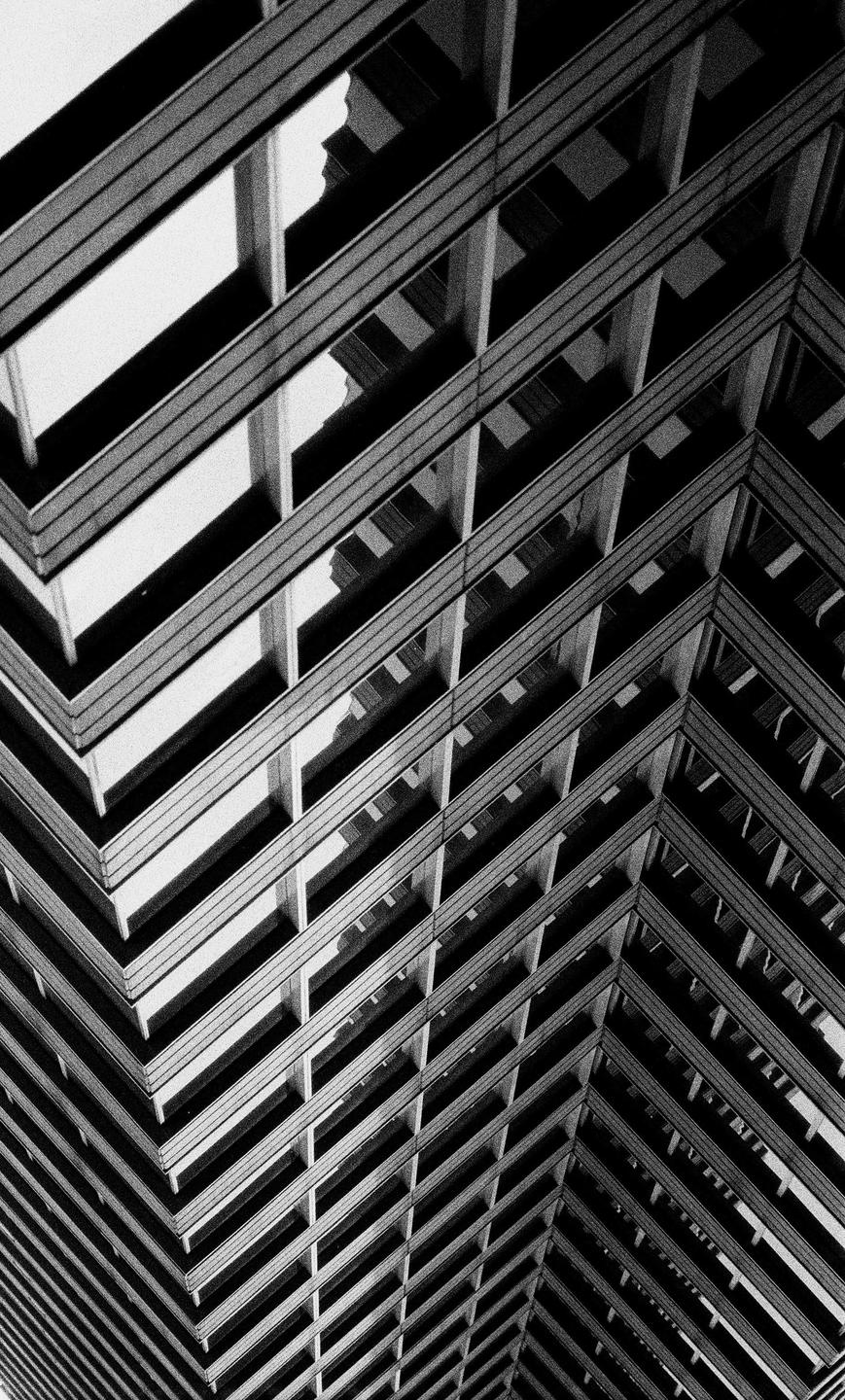 A black and white abstract architectural photograph shows the geometric patterns of a building's facade.