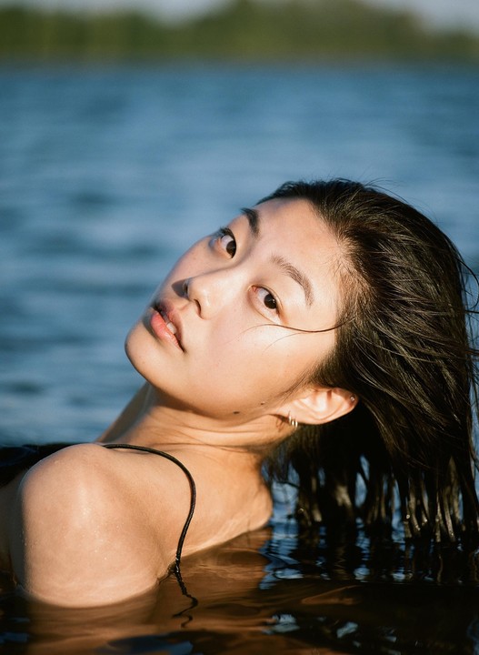 A woman with wet hair is in the water, looking up at the viewer.