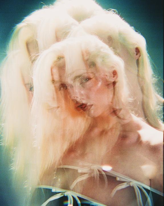 A woman with long blonde hair is depicted in a multiple exposure portrait with a blue background.