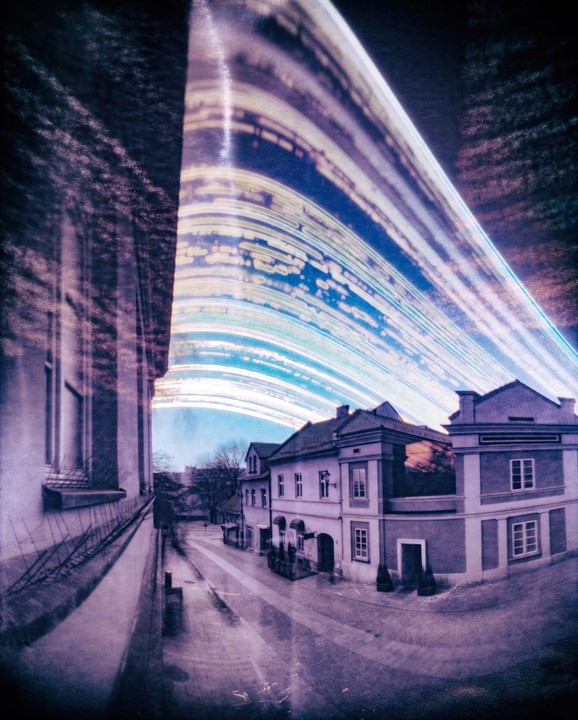 A street with buildings is visible through a distorted, streaked window.
