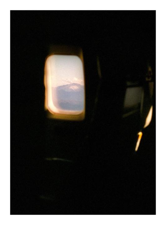 A mountain range is visible through an airplane window.