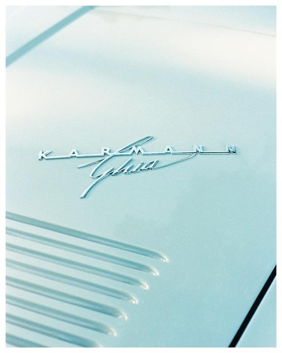 The "Karmann Ghia" emblem is visible on the hood of a light blue car.