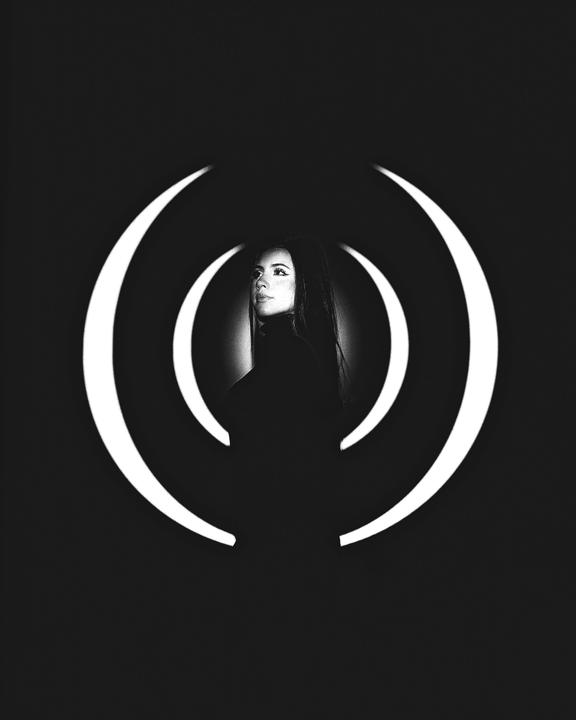 A woman with long hair is framed by concentric white arcs against a black background.