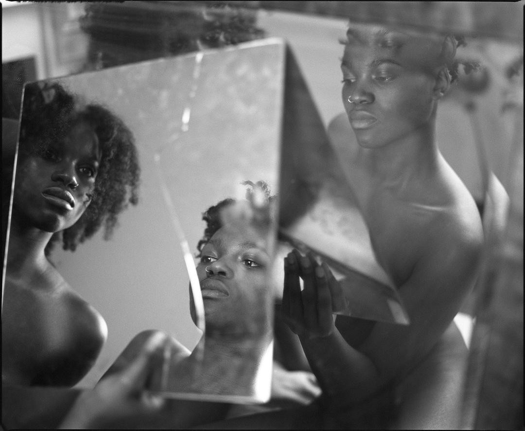 A woman is reflected in multiple mirrors, creating a fragmented portrait.