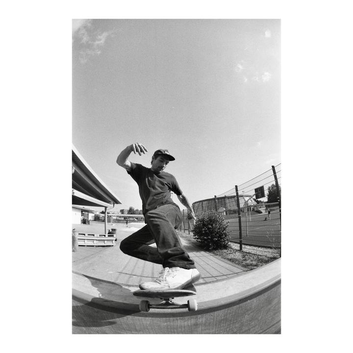 A man on a skateboard rides a concrete ramp at a skatepark.