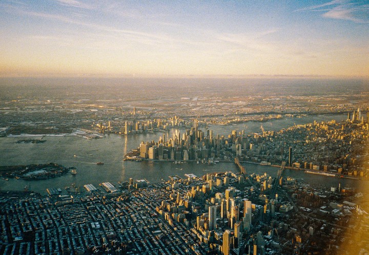 An aerial view shows the New York City skyline and surrounding areas during golden hour.