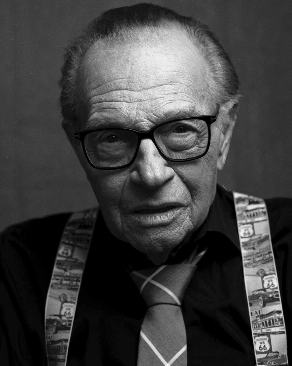 A man wearing glasses, a tie, and suspenders with a Route 66 pattern is looking directly at the viewer.