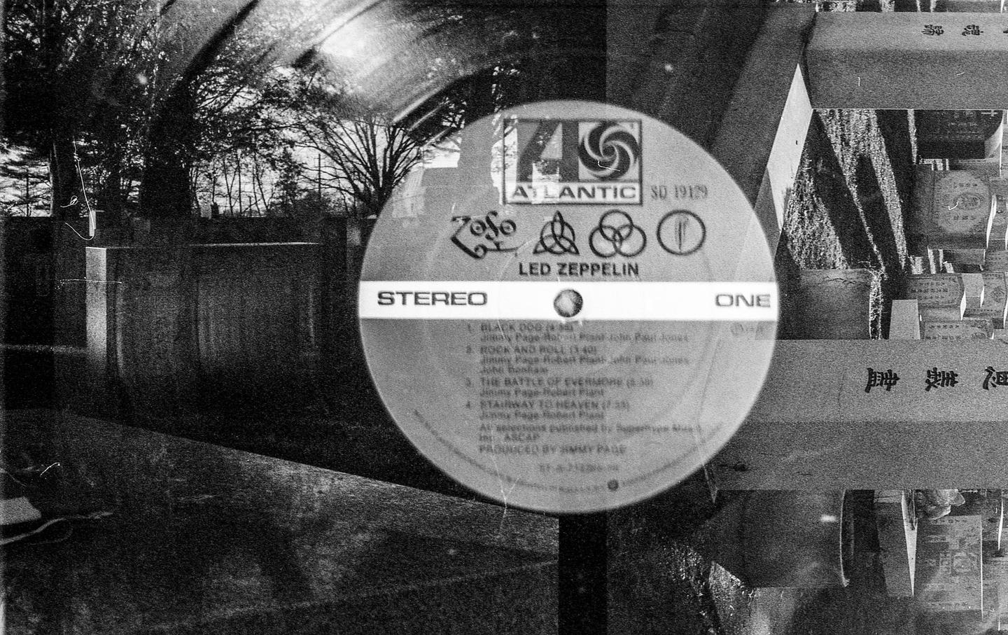 A Led Zeppelin vinyl record is superimposed over a cemetery with trees in the background.