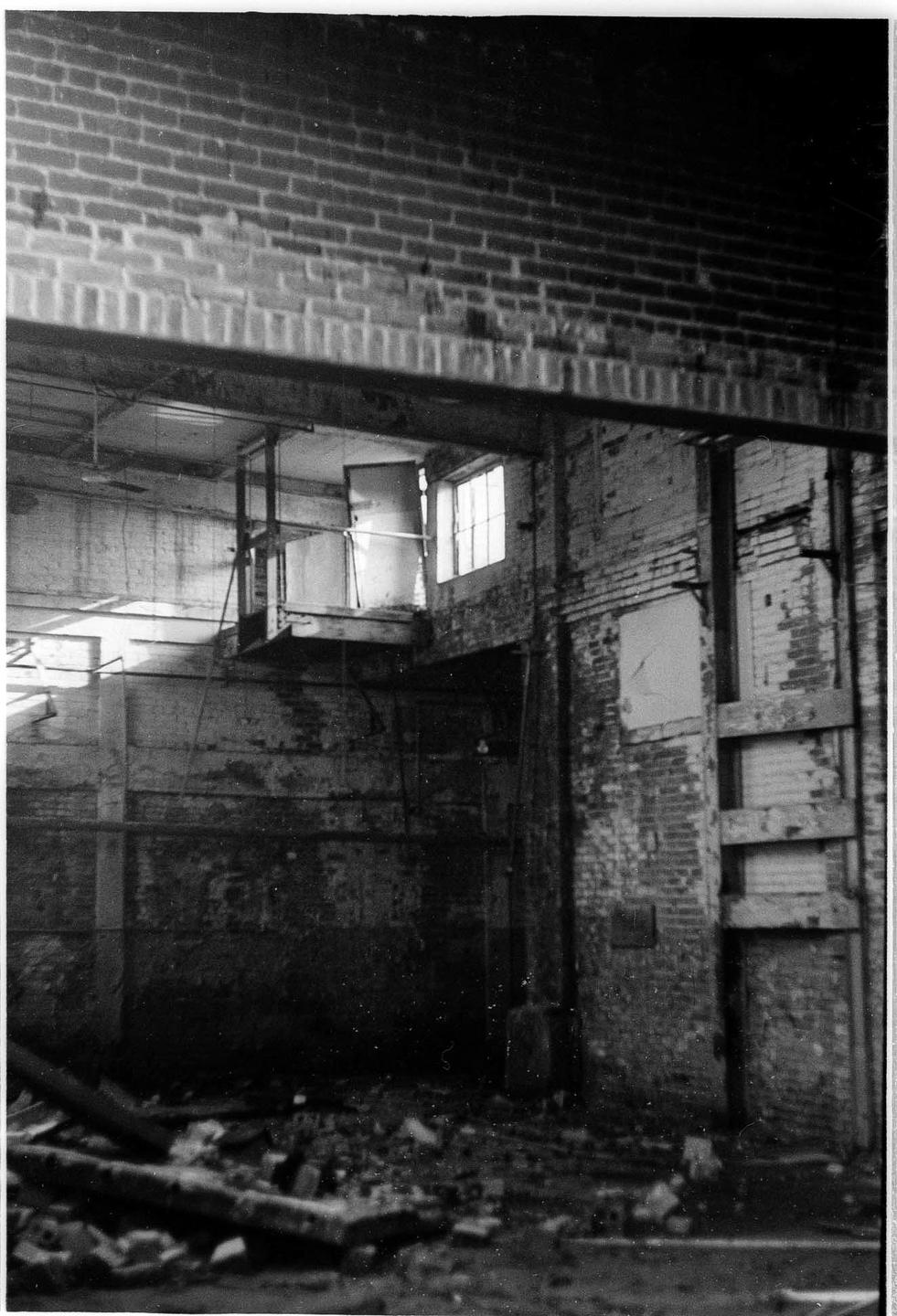 A ruined brick building interior shows debris on the floor and light coming through a window.