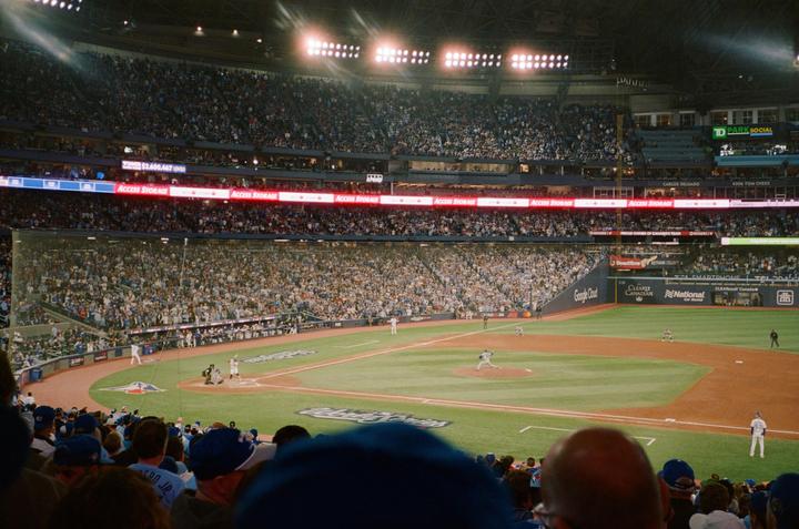 A baseball game is in progress at a stadium filled with spectators under bright lights.