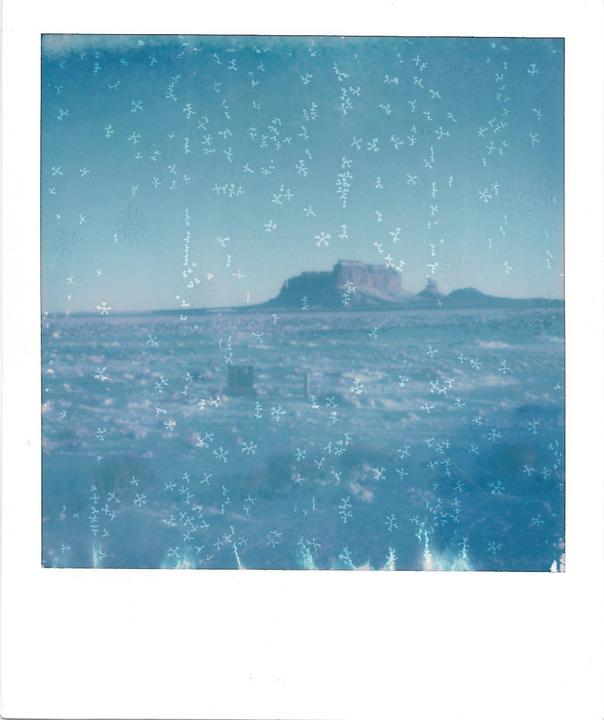 A wide, flat landscape with a mesa in the distance is covered in ice crystals.