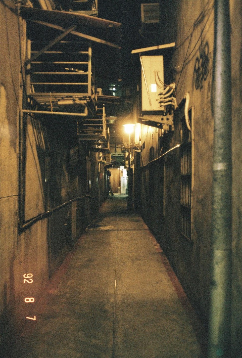 A narrow alleyway is illuminated by a single street light at night.