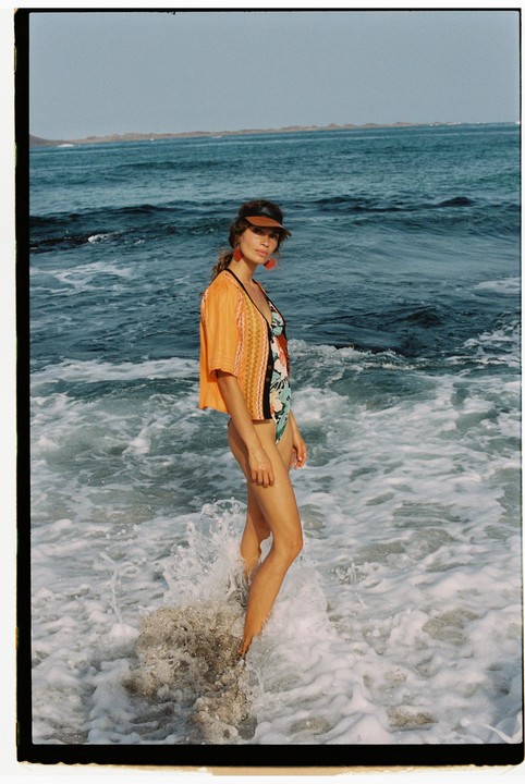 A woman stands in the ocean with waves crashing around her legs.