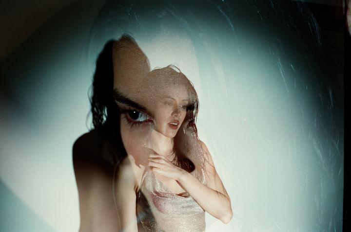 A woman in a shiny top is visible through a double exposure with a large eye.