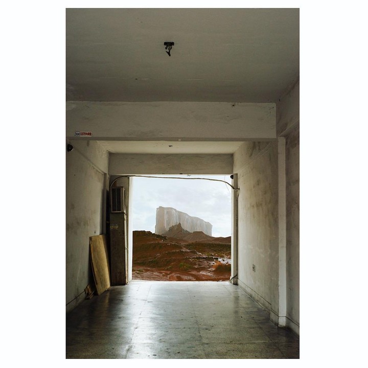 A desert landscape with a large mesa is visible through an open doorway in a building.