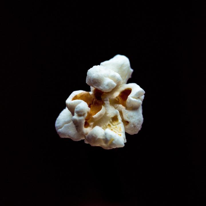 A single piece of popcorn is centered against a dark background.
