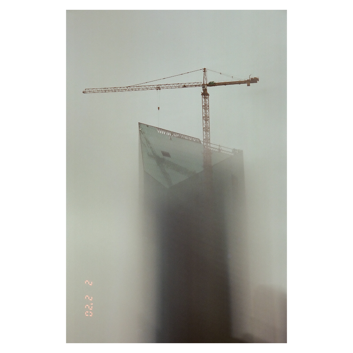 A construction crane is visible above a building shrouded in fog.