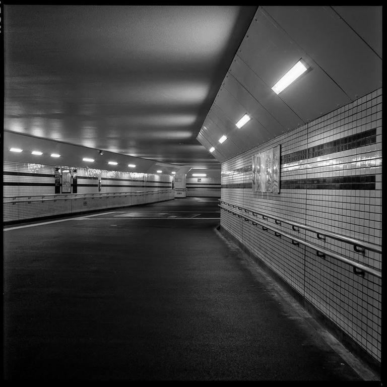 A long, empty, brightly lit pedestrian tunnel curves to the right.