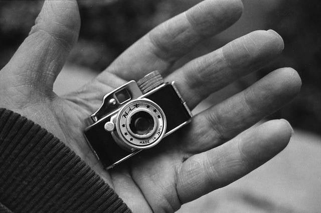 A small camera rests in the palm of a hand.