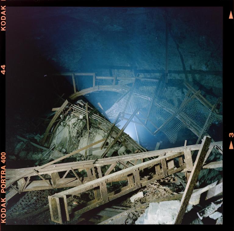 A collapsed underground structure is illuminated by a bright light source.