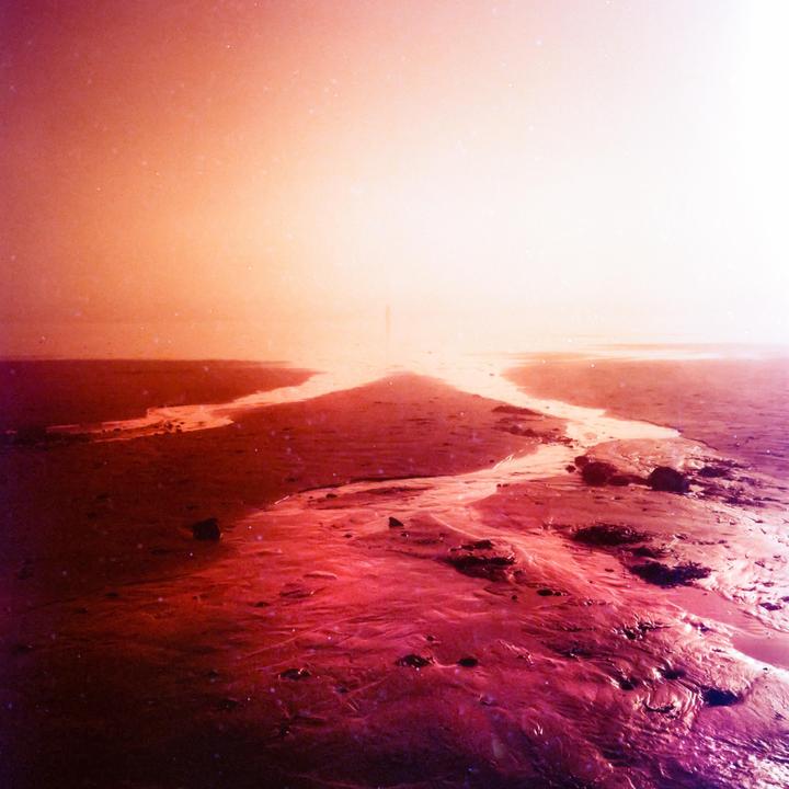 A body of water with a winding stream is visible under a bright sky.