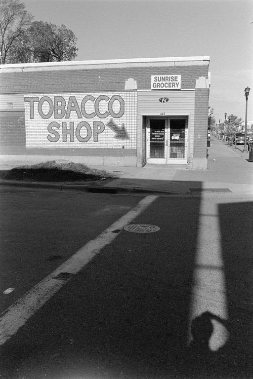A tobacco shop with a "Sunrise Grocery" sign is visible from across the street.