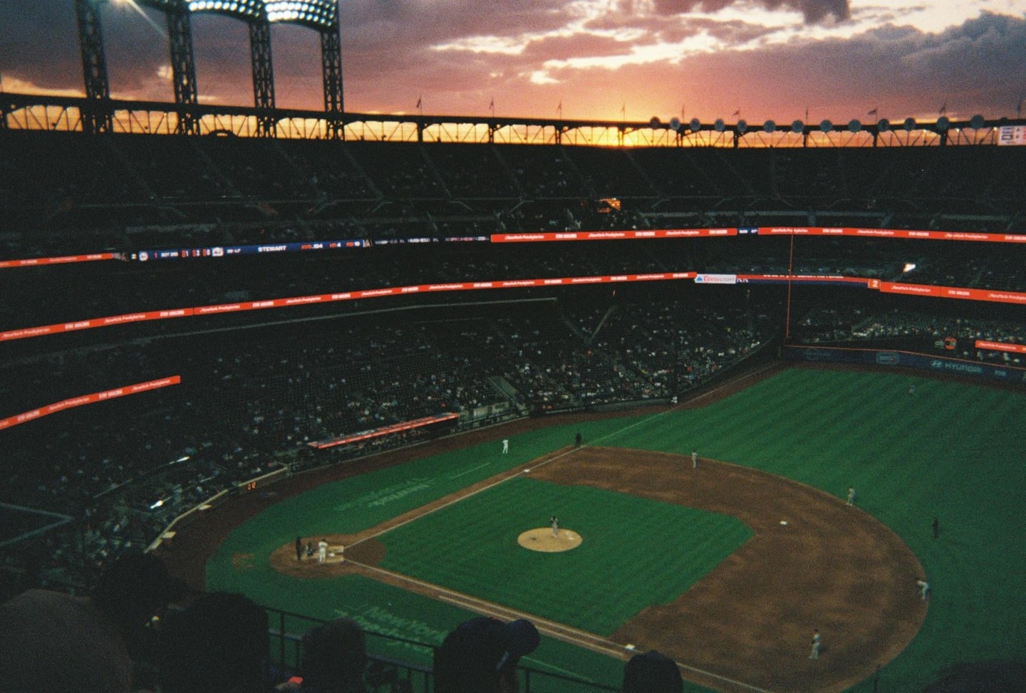 A baseball game is played in a stadium at sunset.