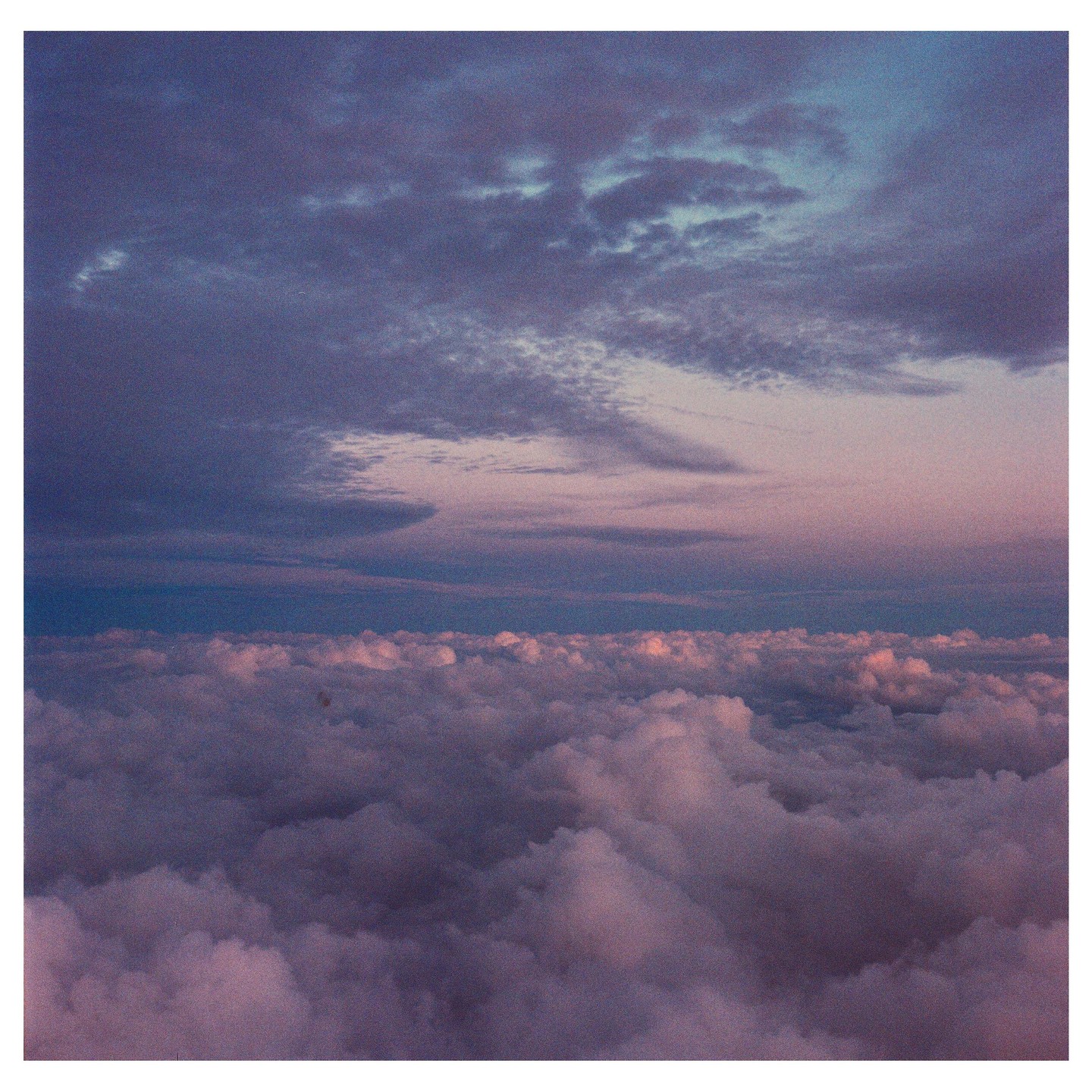 A vast expanse of clouds stretches across the horizon under a colorful sky.
