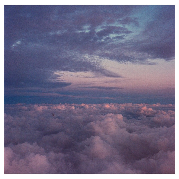 A vast expanse of clouds stretches across the horizon under a colorful sky.