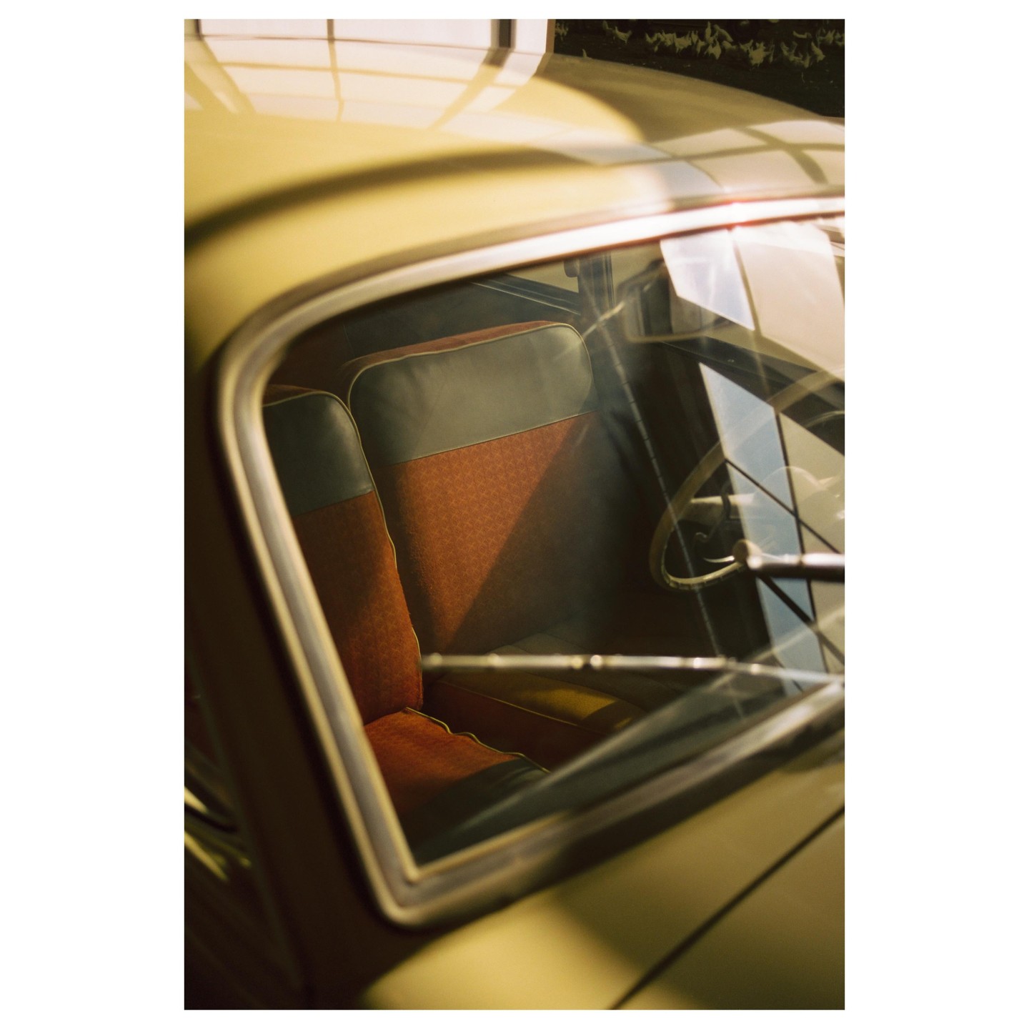 The interior of a vintage car with patterned seats is visible through the side window.