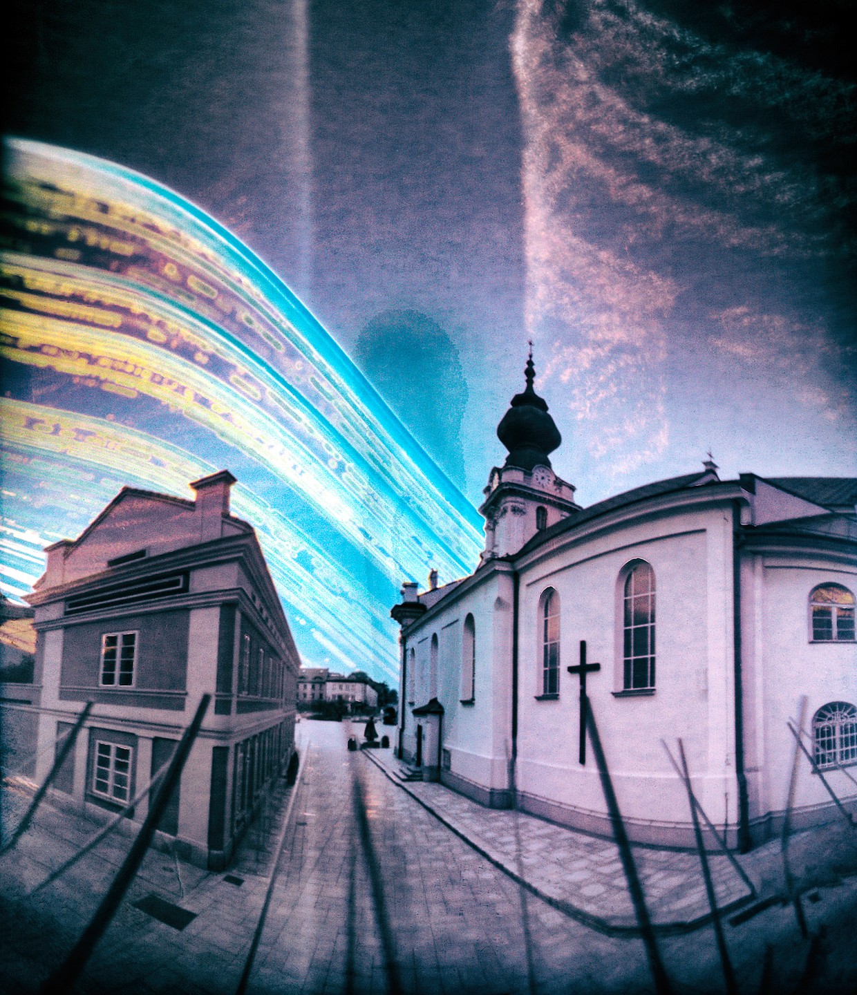 A street with a church and another building is visible under a sky with light trails.