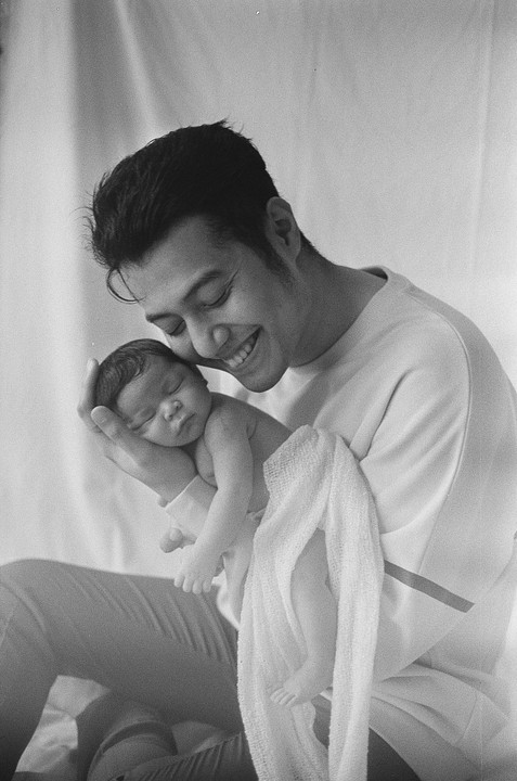 A man holds a sleeping baby in his arms.