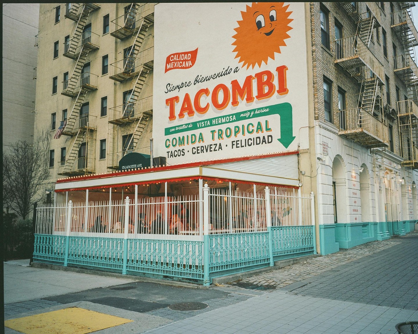 A restaurant with a large mural on its side is visible from a street corner.