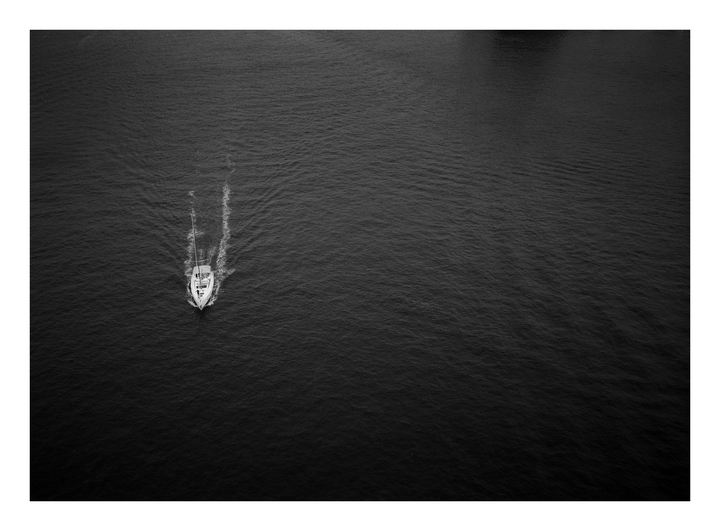 A sailboat moves through the water, leaving a wake behind it.